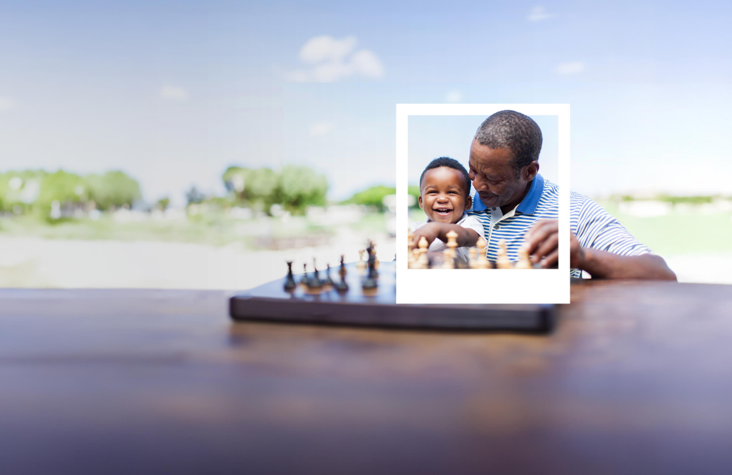 Grandfather laughing and playing chess with his grandson on his lap. 