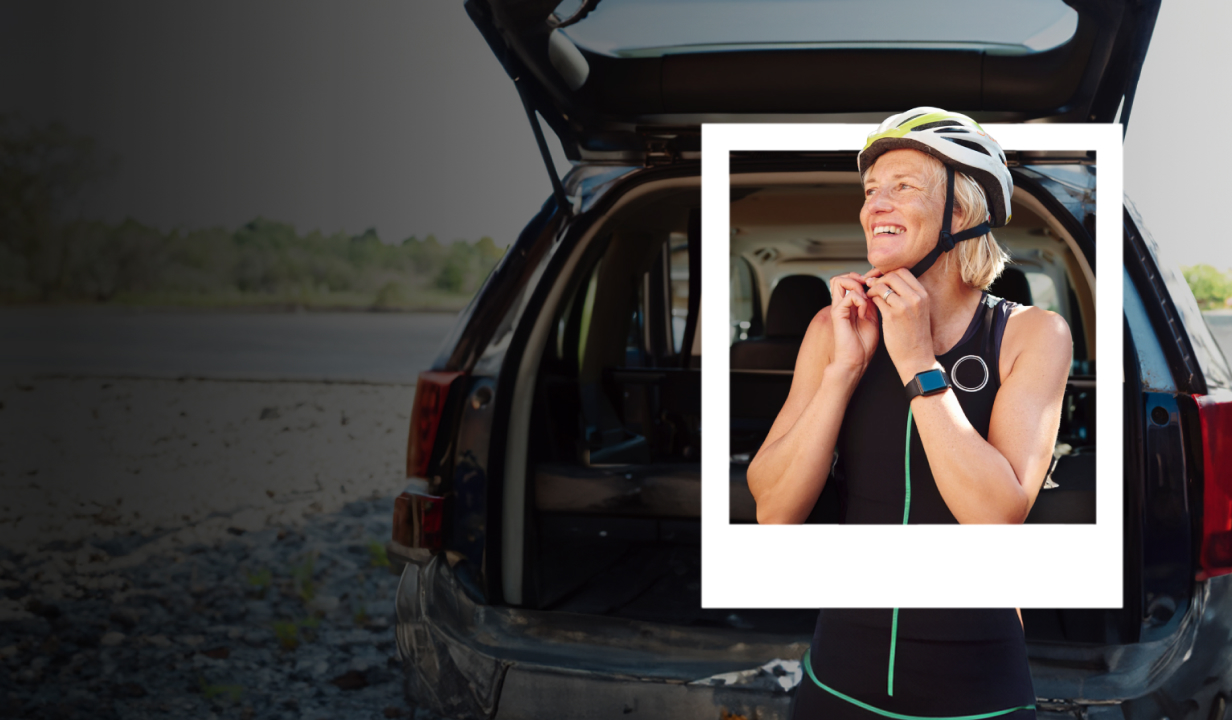 Woman clipping her bicycle helmet closed in front of an open car trunk.