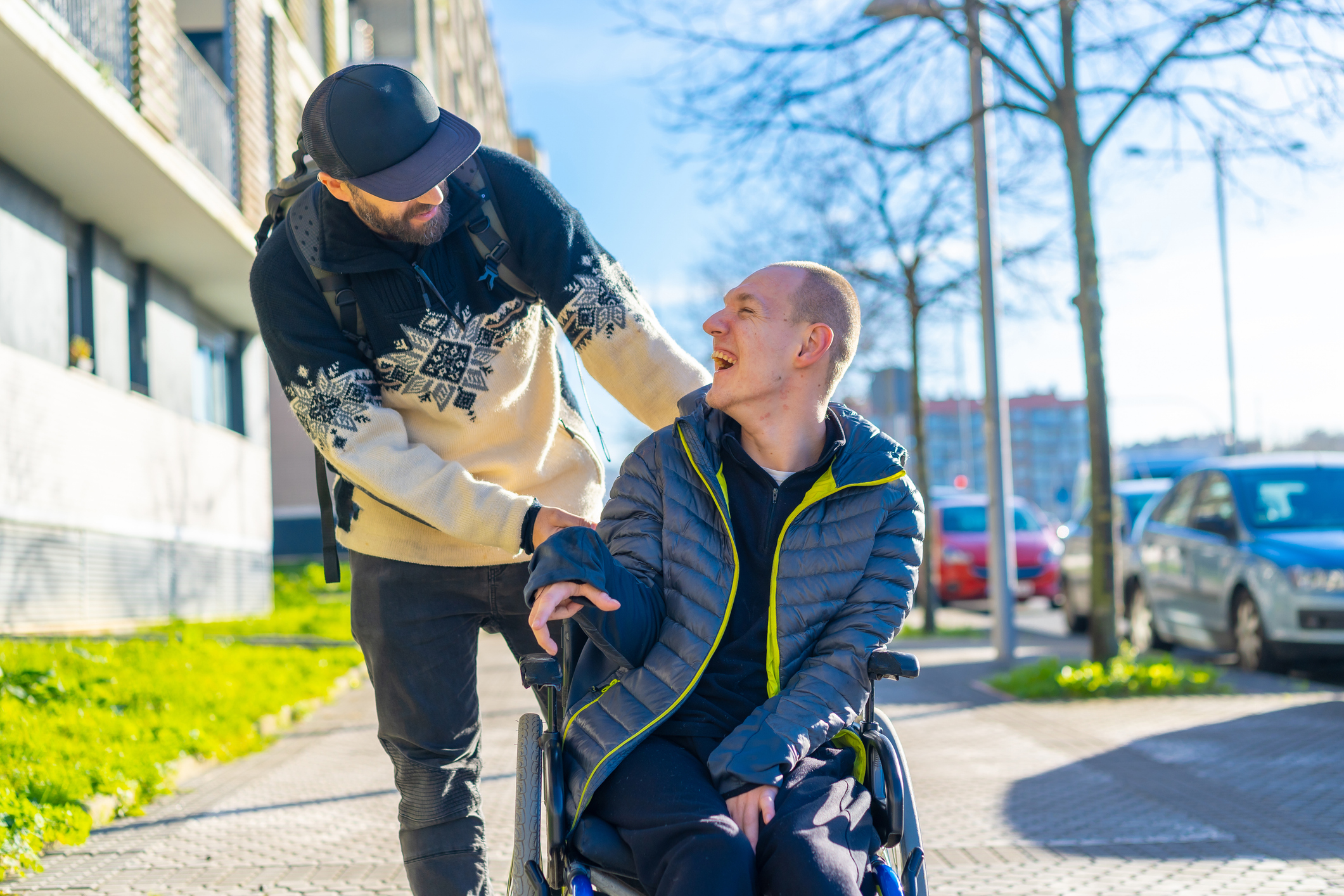 A disabled person in a wheelchair with a friend smiling