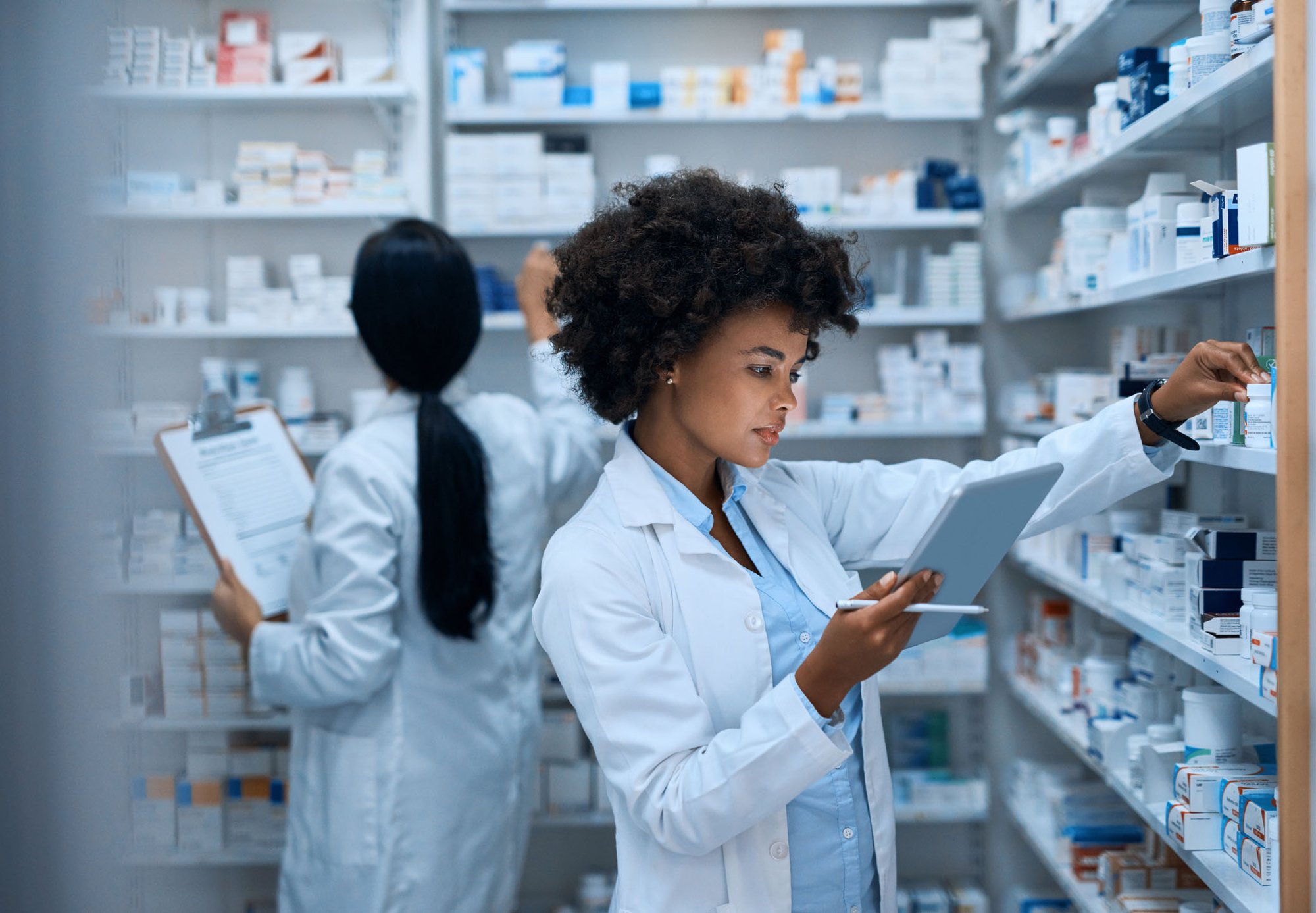 Young female pharmacist reviews an ipad while fulfilling an order